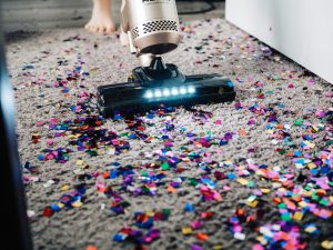 Sola professional vacuum cleaner removing colorful confetti from a grey carpet during an emergency cleaning session.