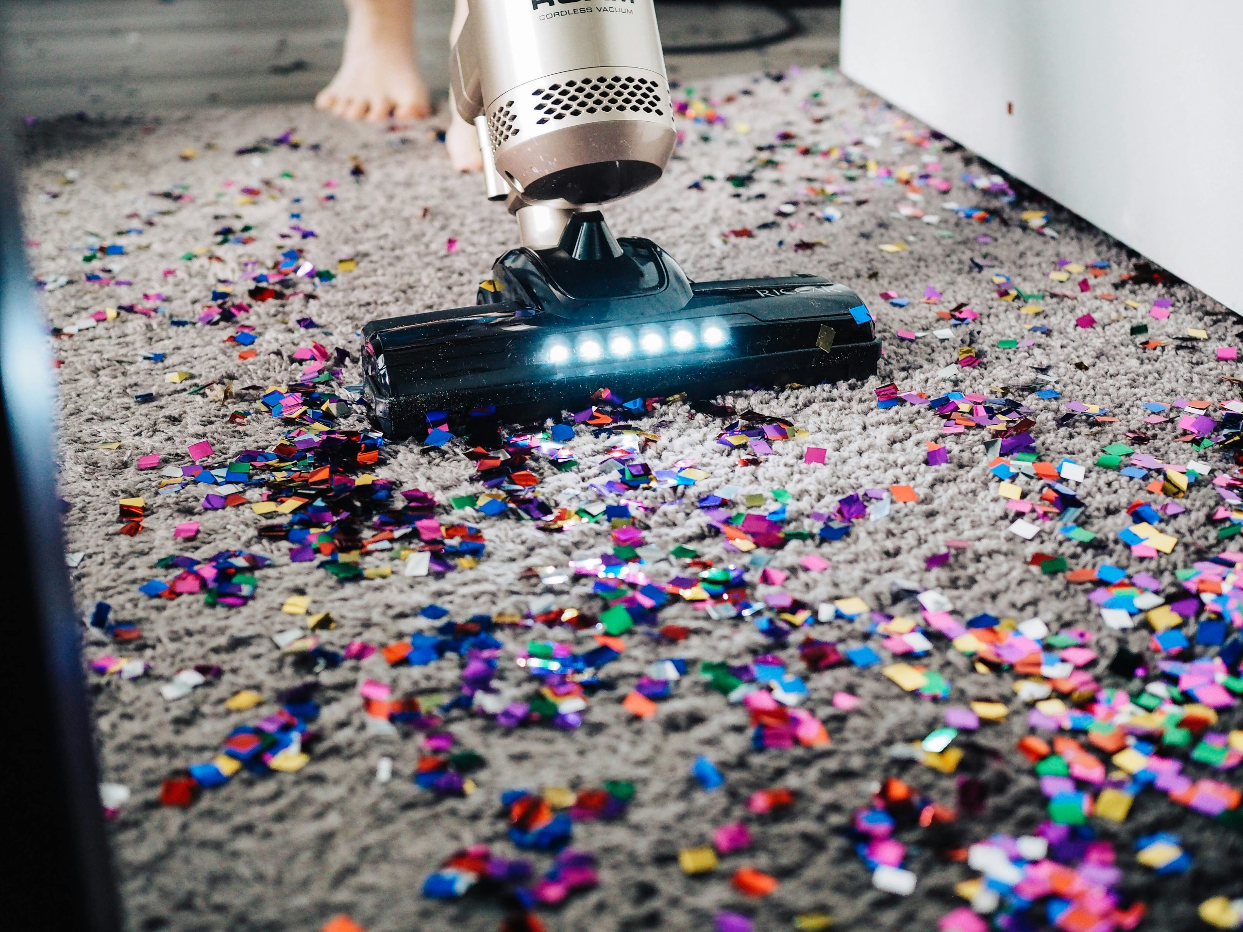 Sola professional vacuum cleaner removing colorful confetti from a grey carpet during an emergency cleaning session.